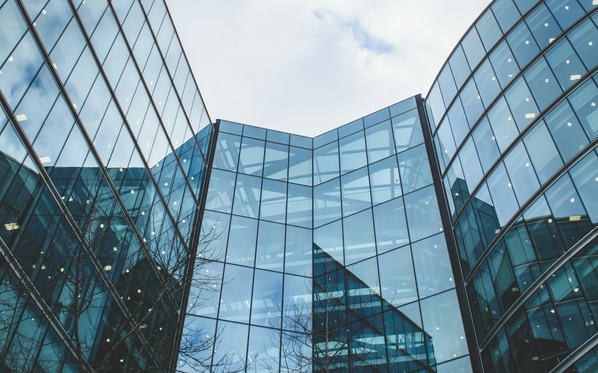 The faceted glass facade of a modern office tower, seen from below.