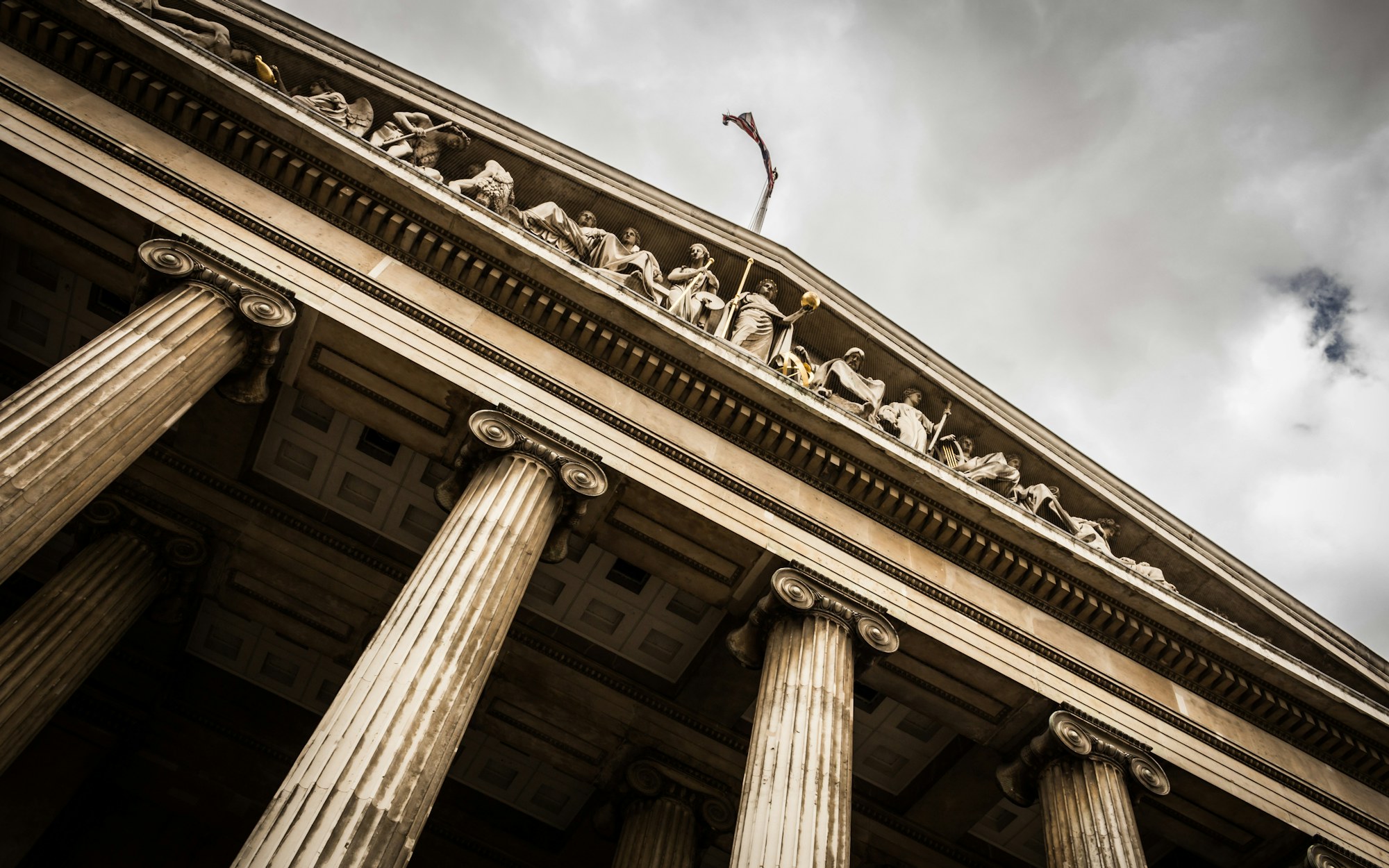 The columned stone portico of a courthouse against an overcast sky.