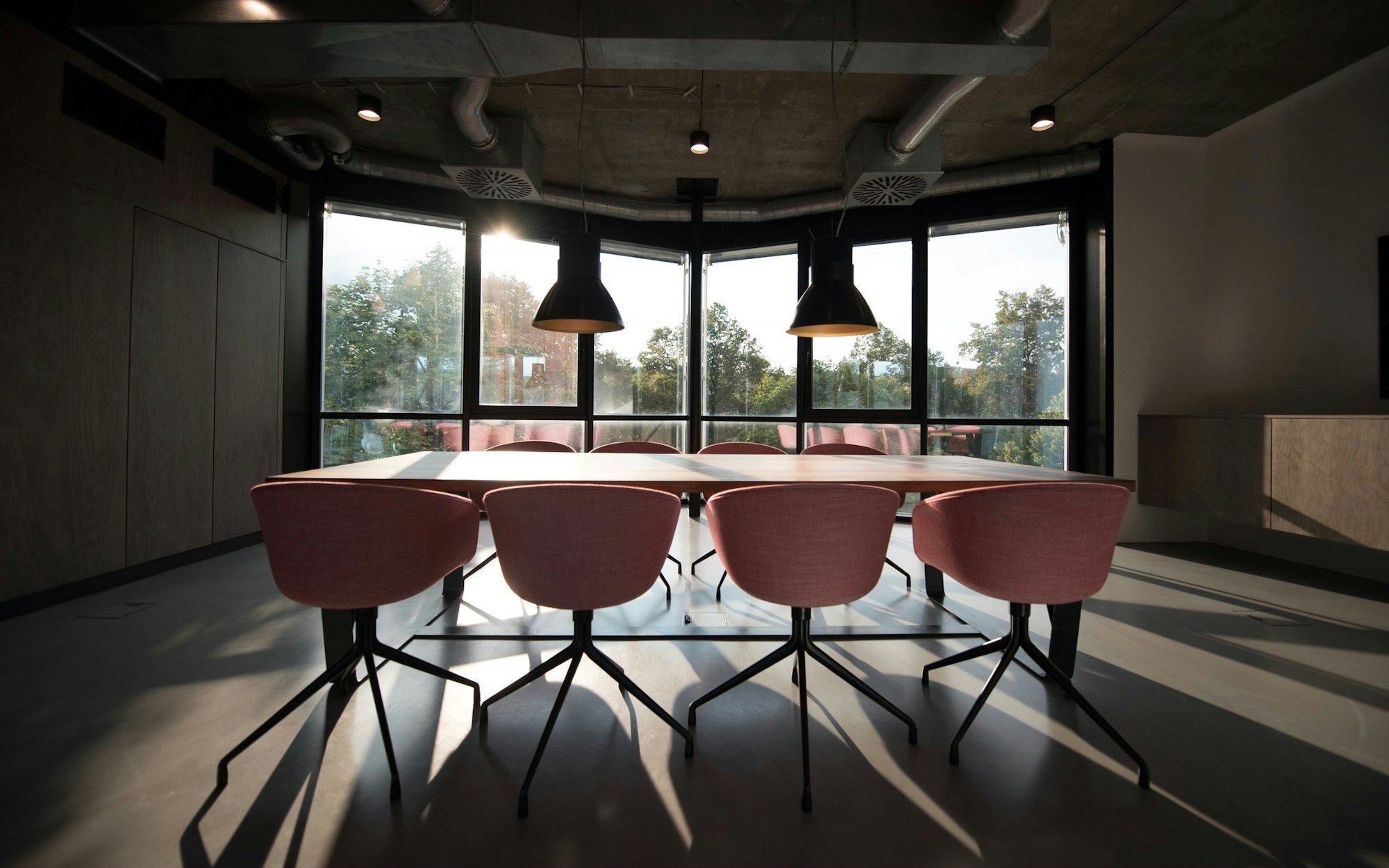 A quiet meeting room with daylight falling across a long bare table.